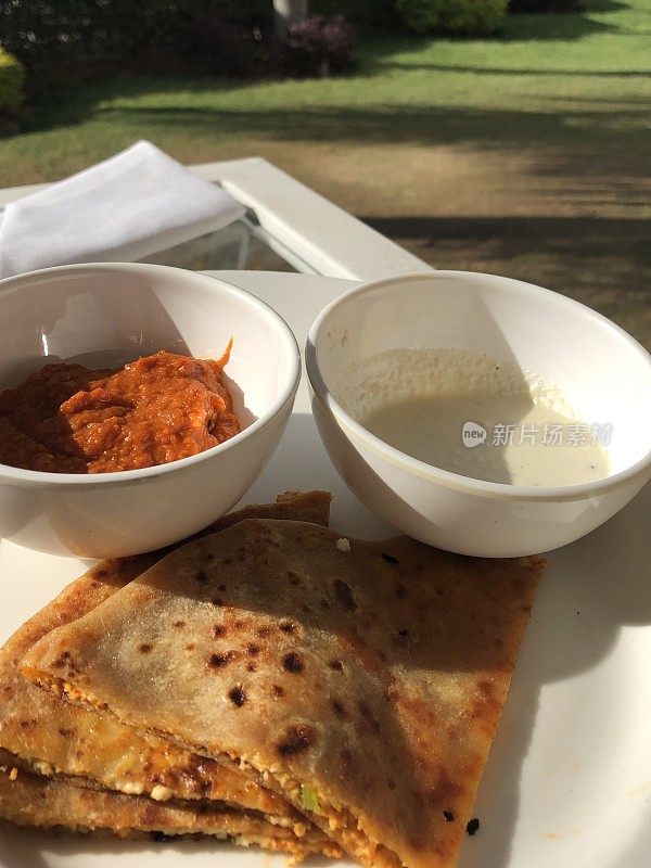 印度德里的北印度自助早餐，配以番茄酸辣酱的白色盘子里的奶酪/白干酪，塞满辣奶酪和洋葱的美味面包，酒店餐厅自制的奶酪